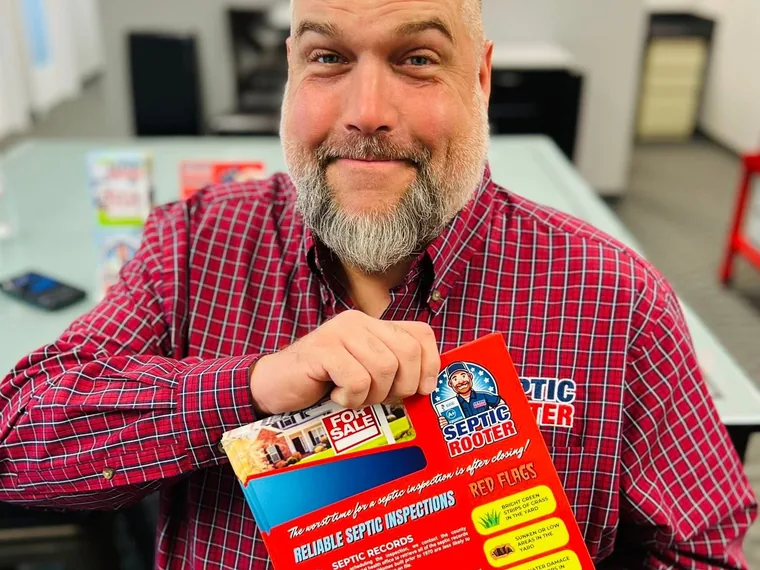 SepticRooter owner holding real estate septic inspection handouts at a class